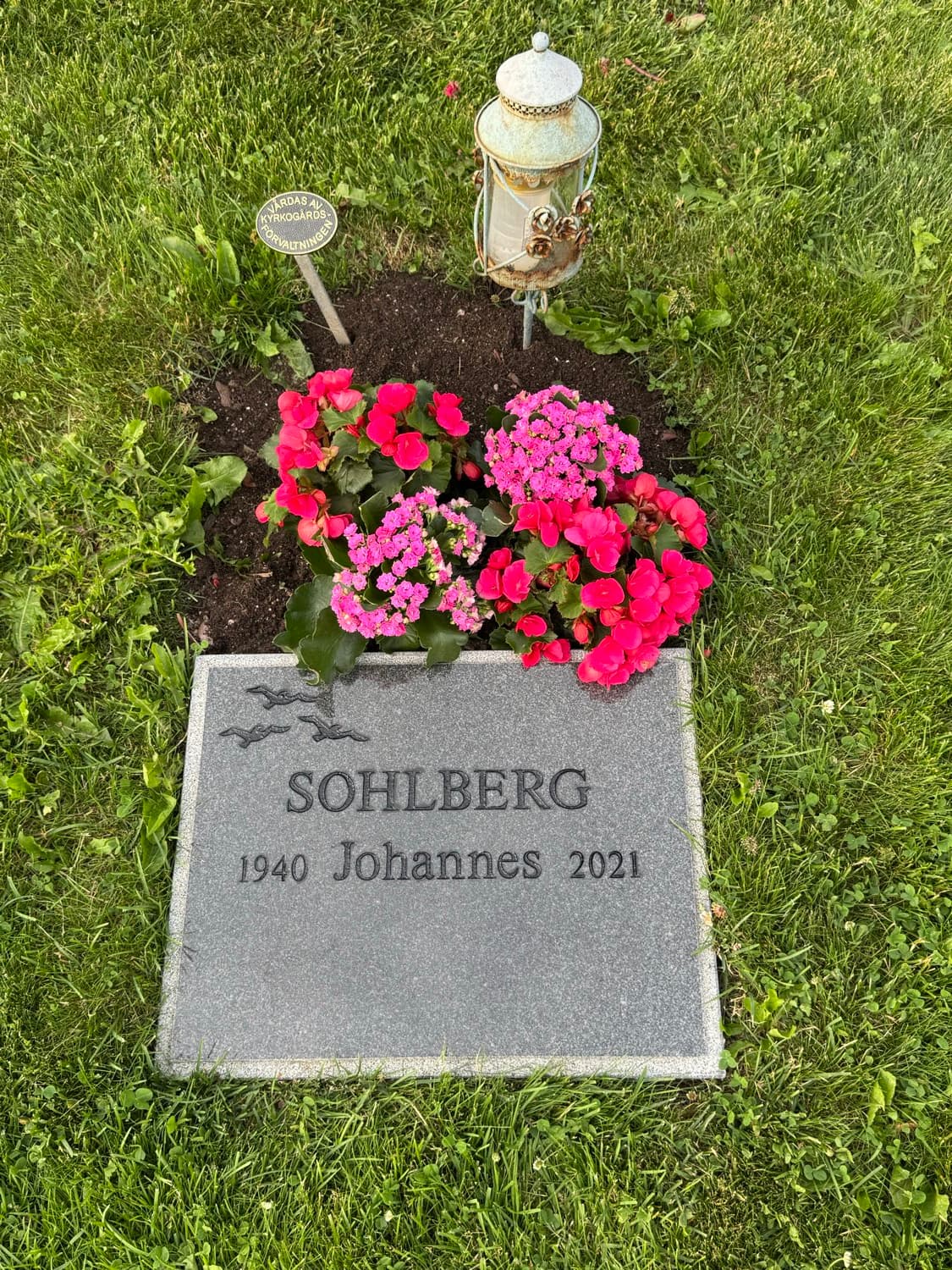 Samma grav efter – blommor i full blom och tydligt ifylld text på gravstenen
