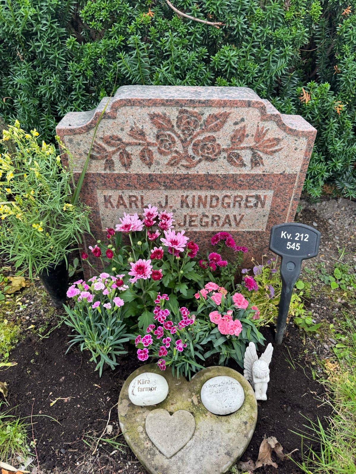 Färdig säsongsplantering vid gravsten med rosa och lila blommor